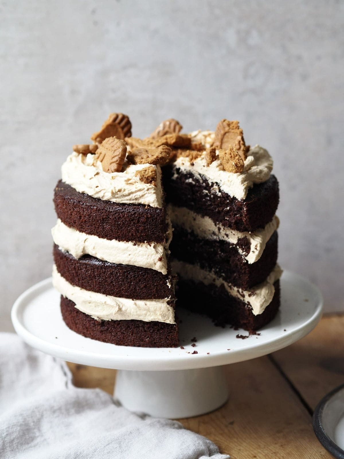Biscoff cake with a slice removed on cake pedestal.
