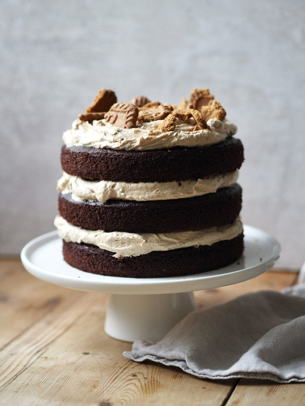 whole biscoff cake on a white cake stand.
