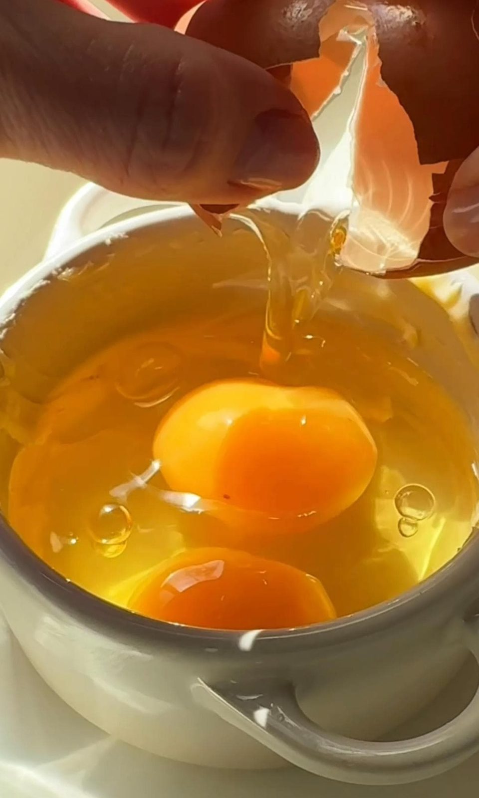 cracking eggs into a ramekin.