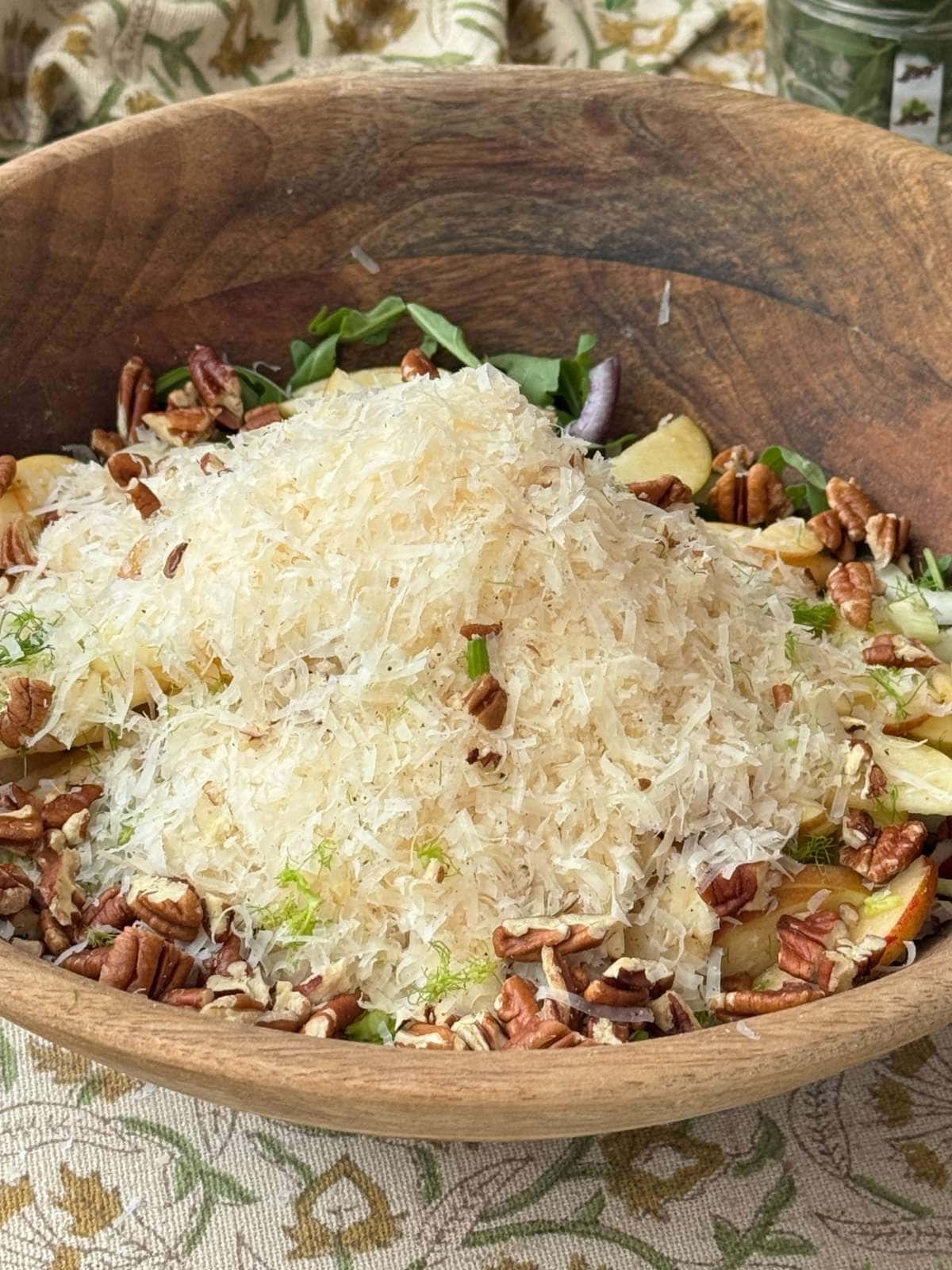 fennel apple salad in a wooden bowl covered with manchego.