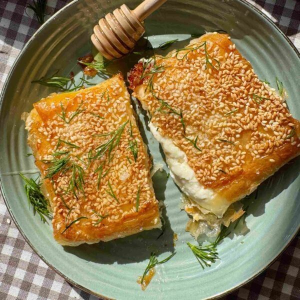 feta saganaki cut in half on a green plate with honey and dill.