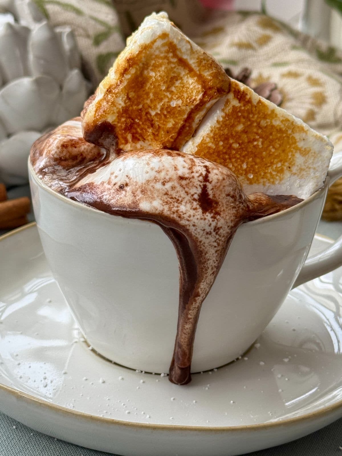 French hot chocolate topped with giant marshmallow in cup on saucer.