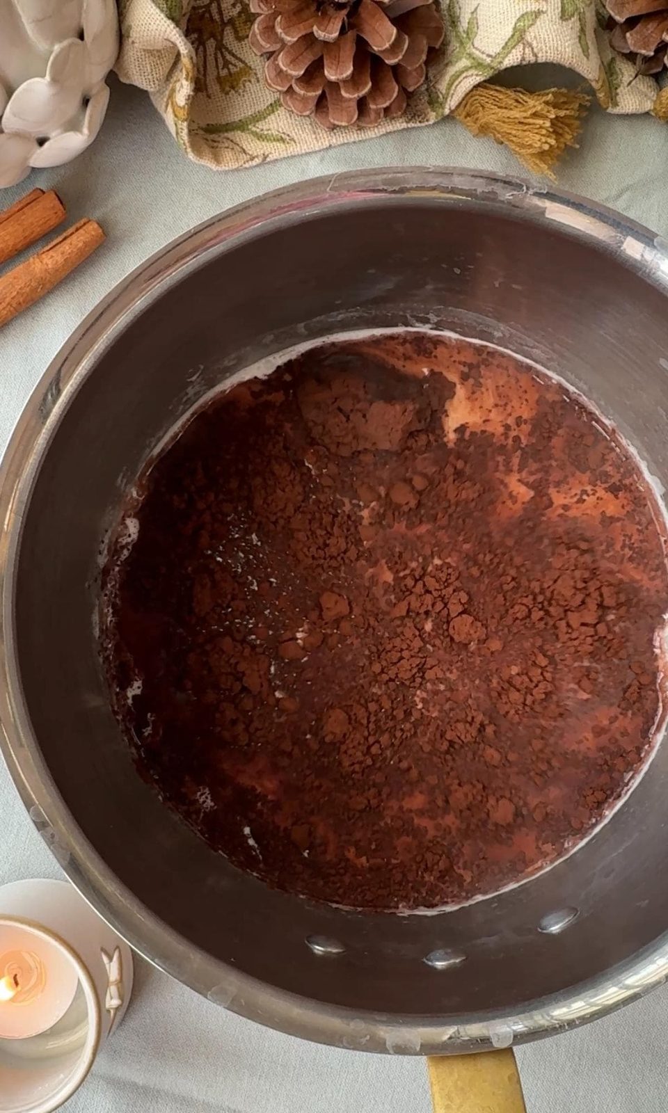 Adding cocoa powder to warm milk in pan.