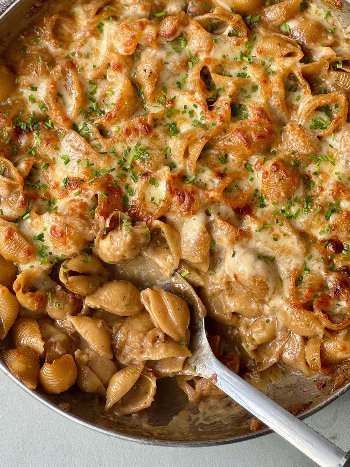 Spooning French onion soup pasta from dish.