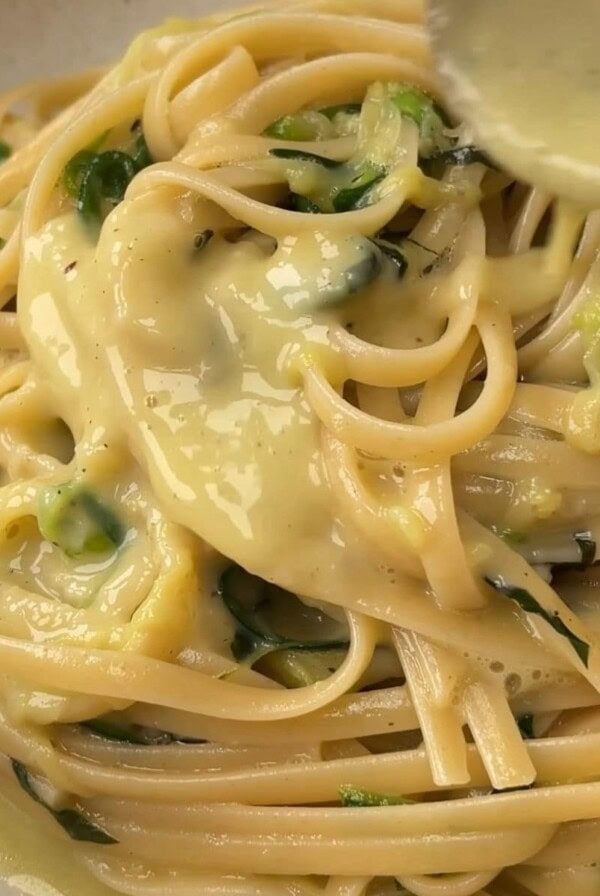 courgette carbonara pouring sauce over pasta.