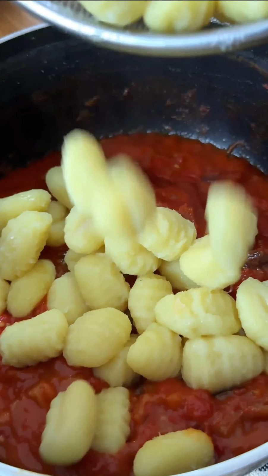 adding gnocchi to tomato sauce.