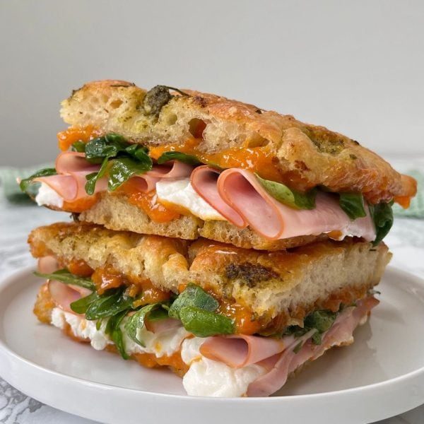 goat cheese focaccia with ham and apricot jam on white plate.