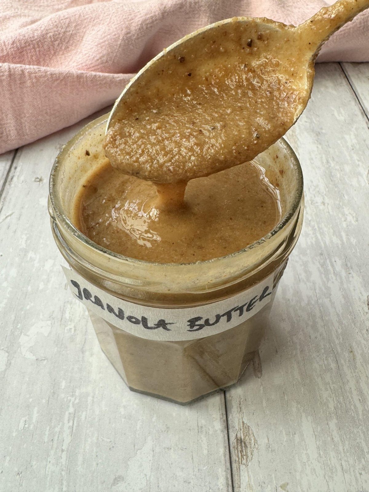 a jar of granola butter with a spoon and a label that reads granola butter.