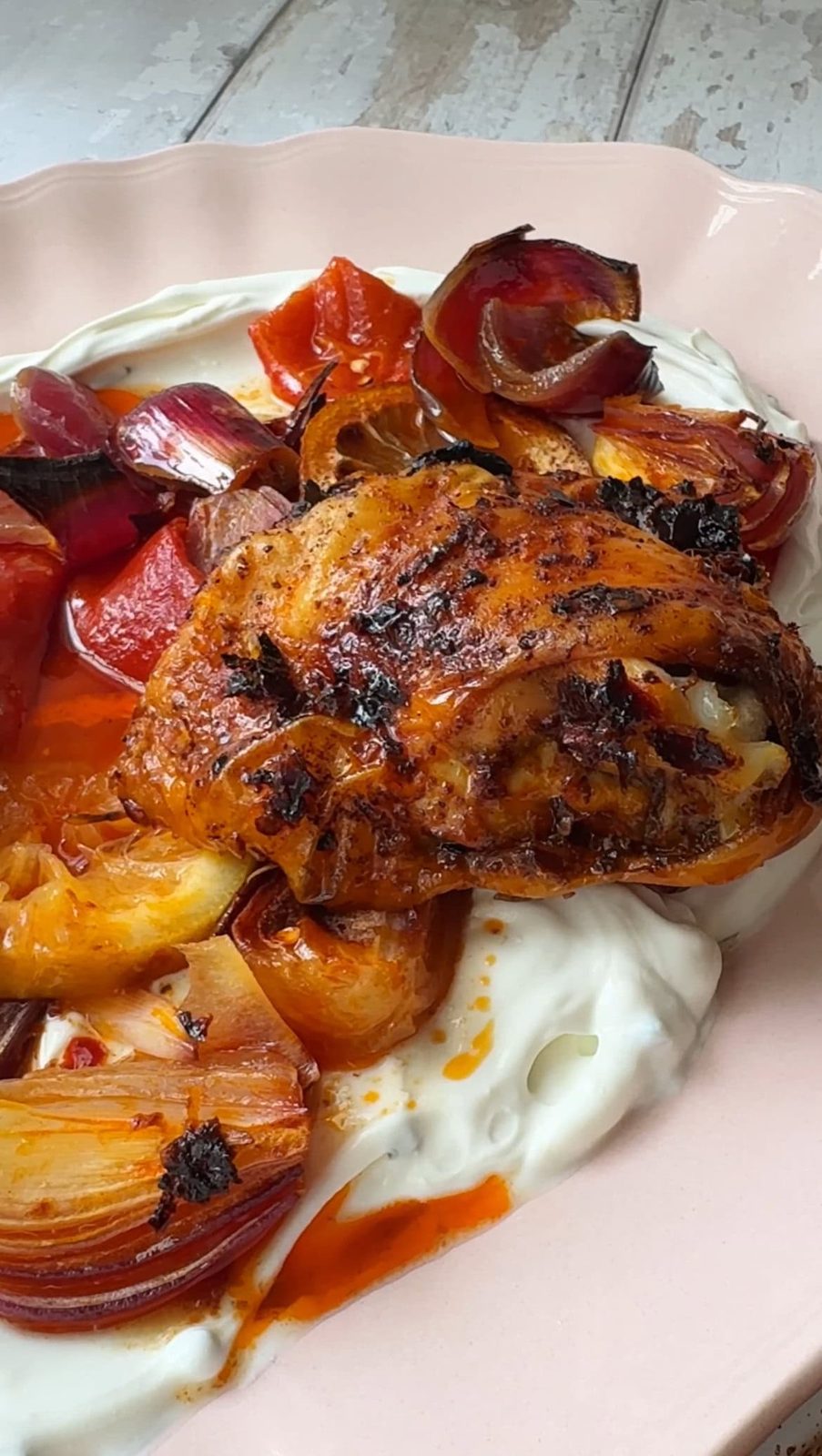 Serving harissa chicken over labneh on plate.