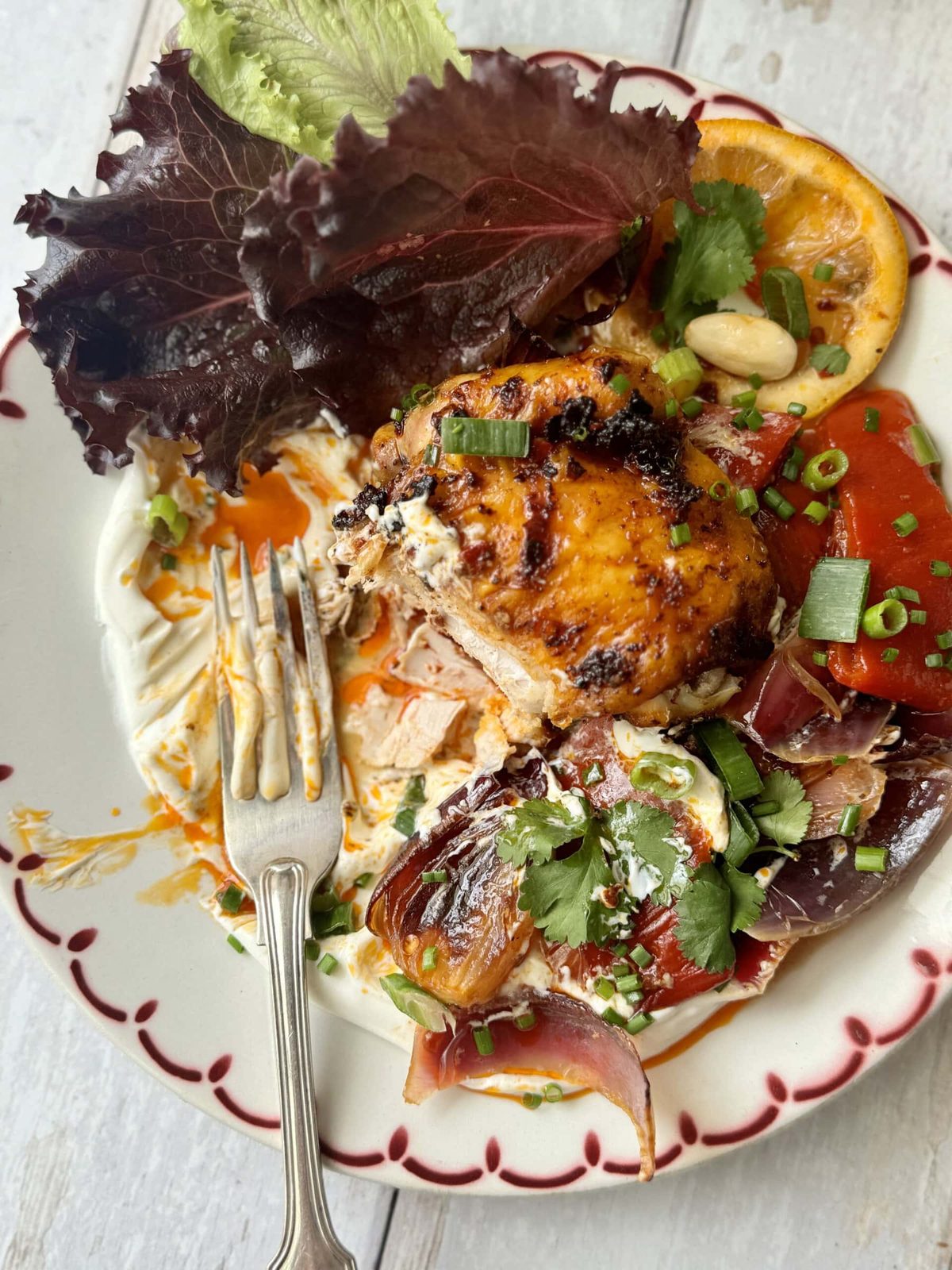 Harissa chicken on platter with labneh, veggies, and salad.