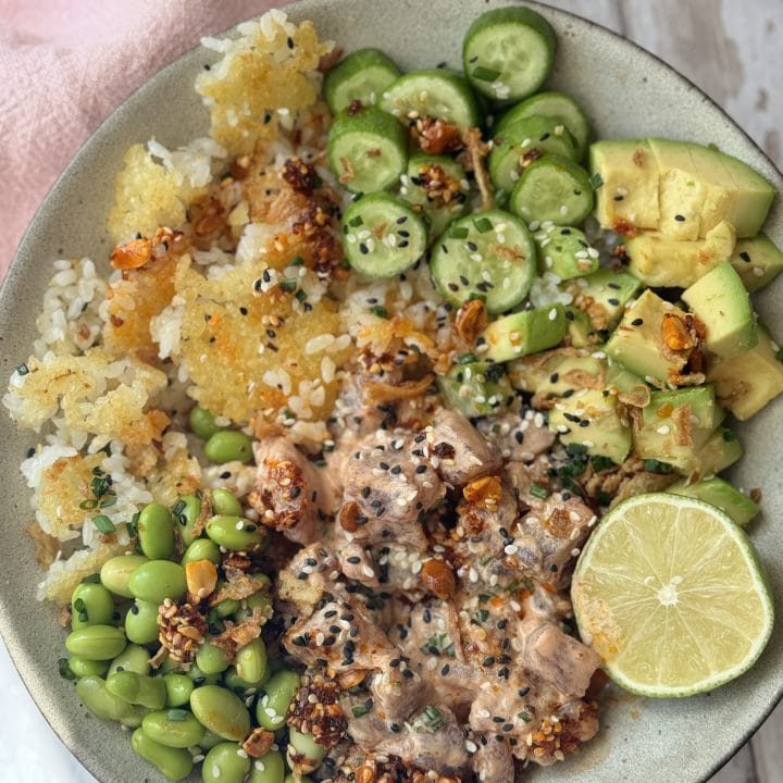 Spicy tuna in a bowl with crispy rice and cucumber and avocado.