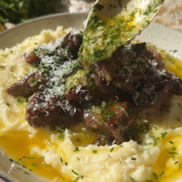 pouring garlic butter over garlic steak bites.
