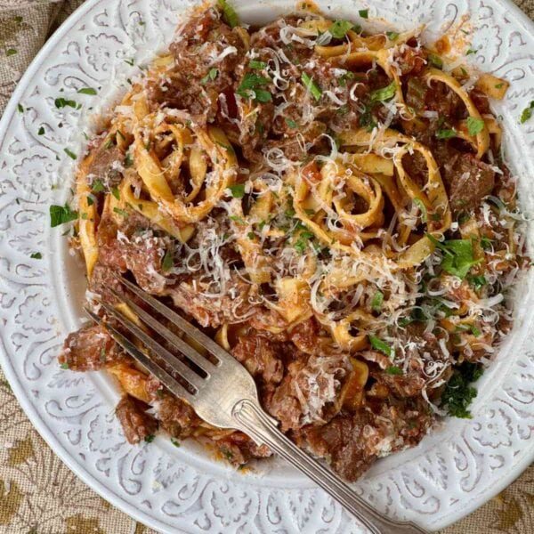 beef shin ragu with tagliatelle in a white bowl.