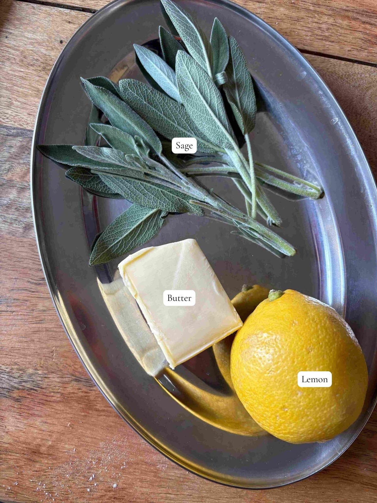 Fresh sage and lemon with butter on tin plate.
