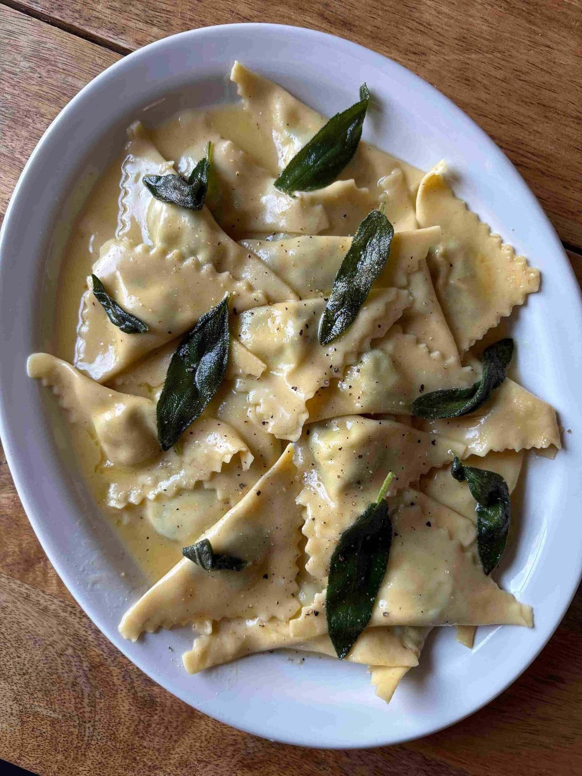 Triangoli filled with spinach and ricotta with butter on white plate.