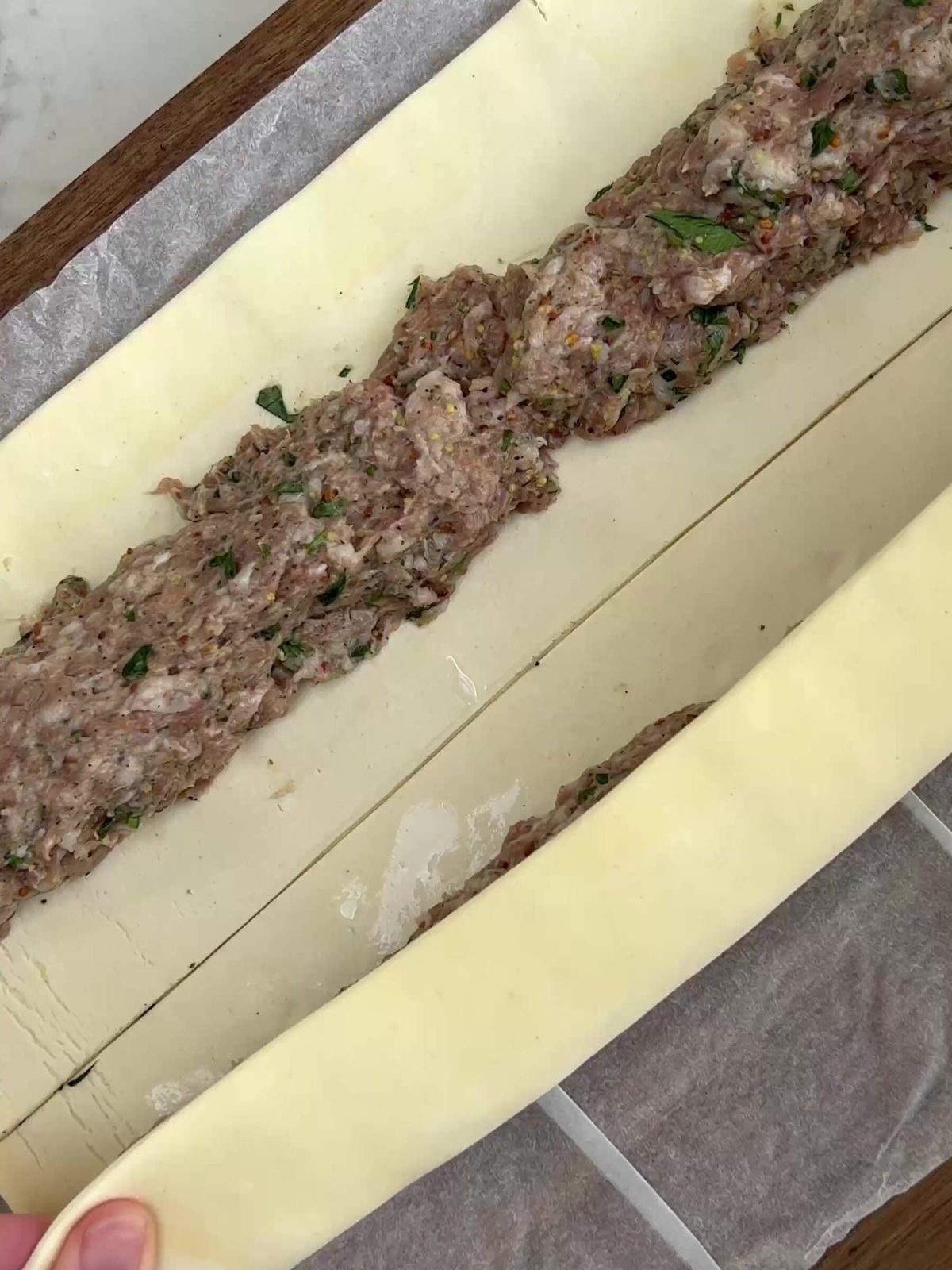 Filling the pastry with sausage meat to make rolls.