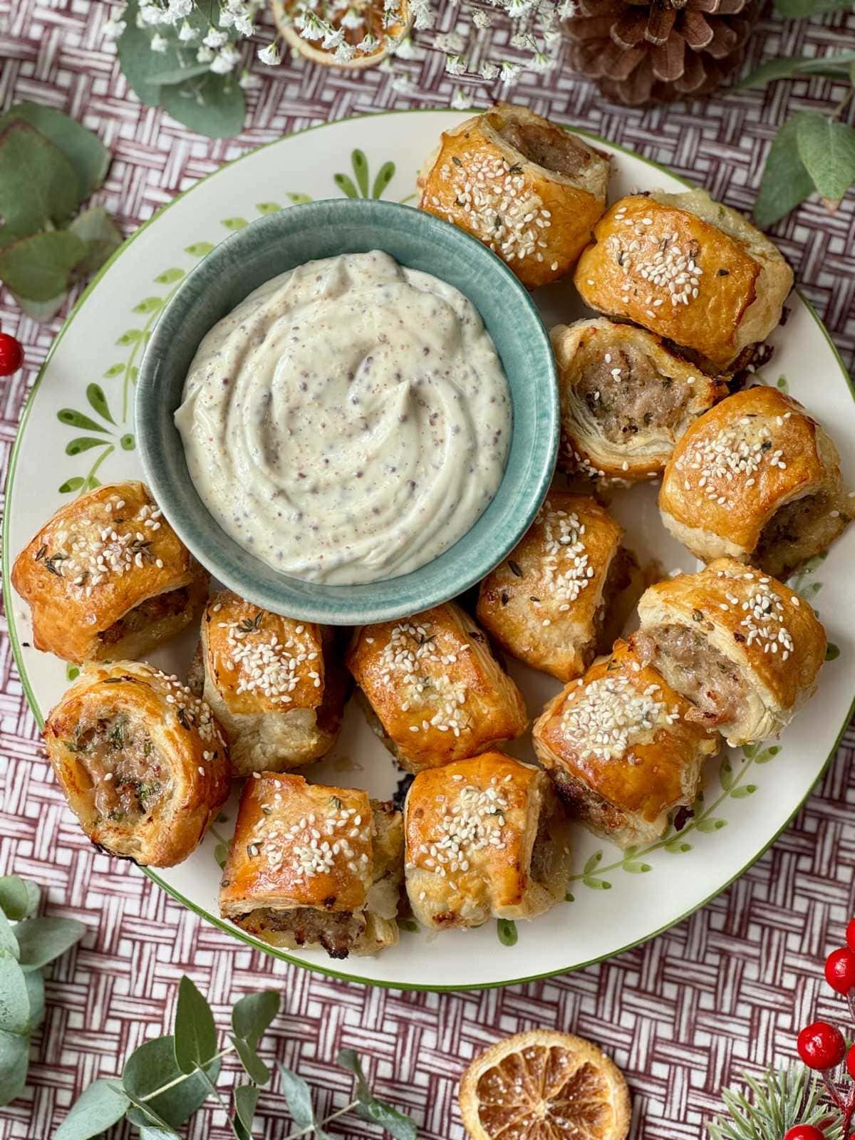 Sausage rolls on plate with honey mustard drizzle and sauce.