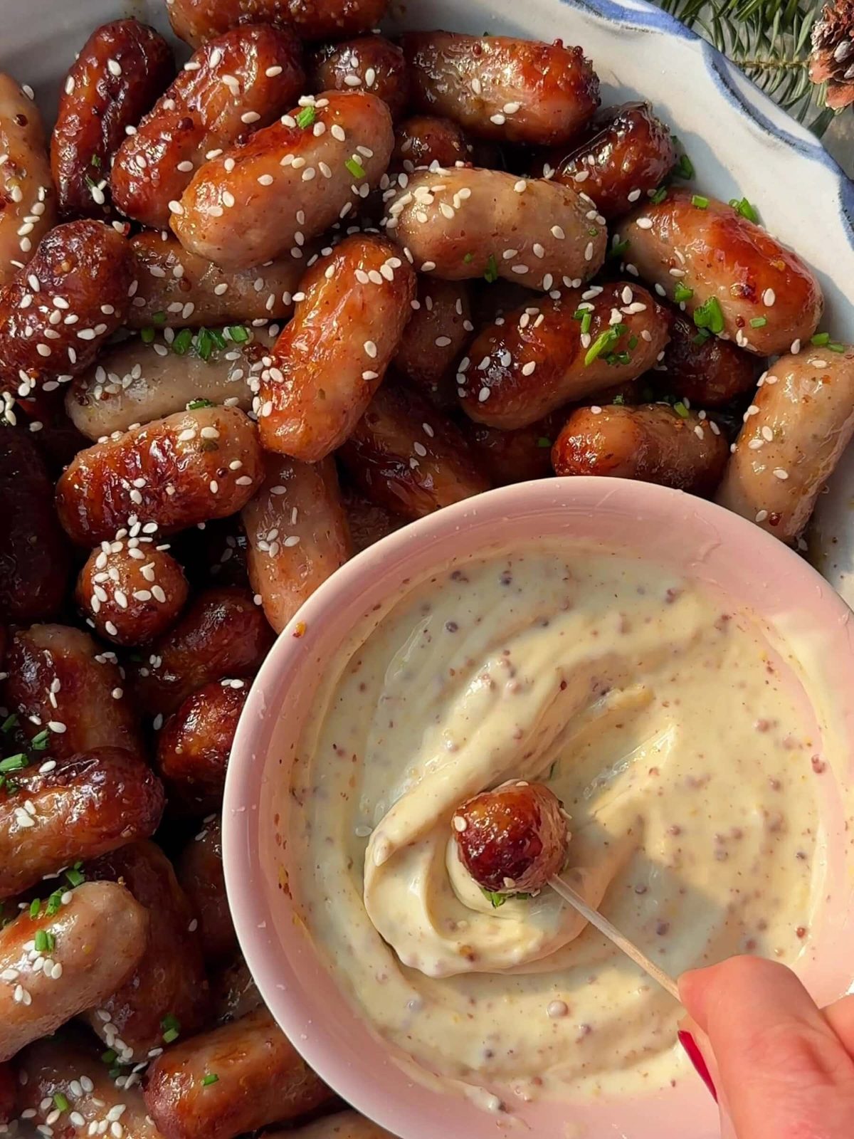 Dipping a sausage in a bowl of spiced mayonnaise.