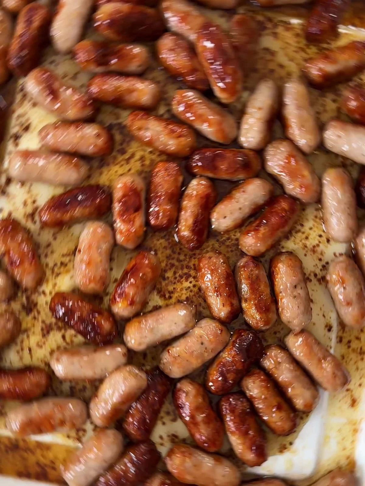 Fried sausages with honey mustard sauce in a baking pan.