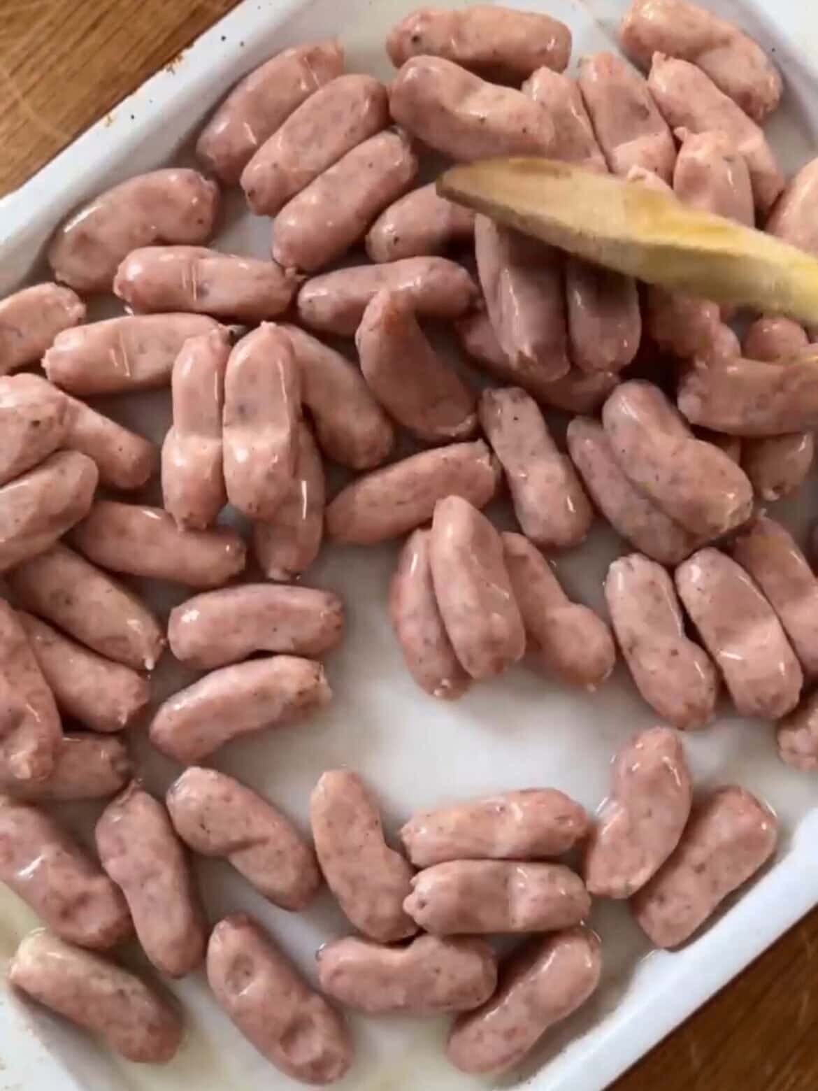Raw cocktail sausages in pan.