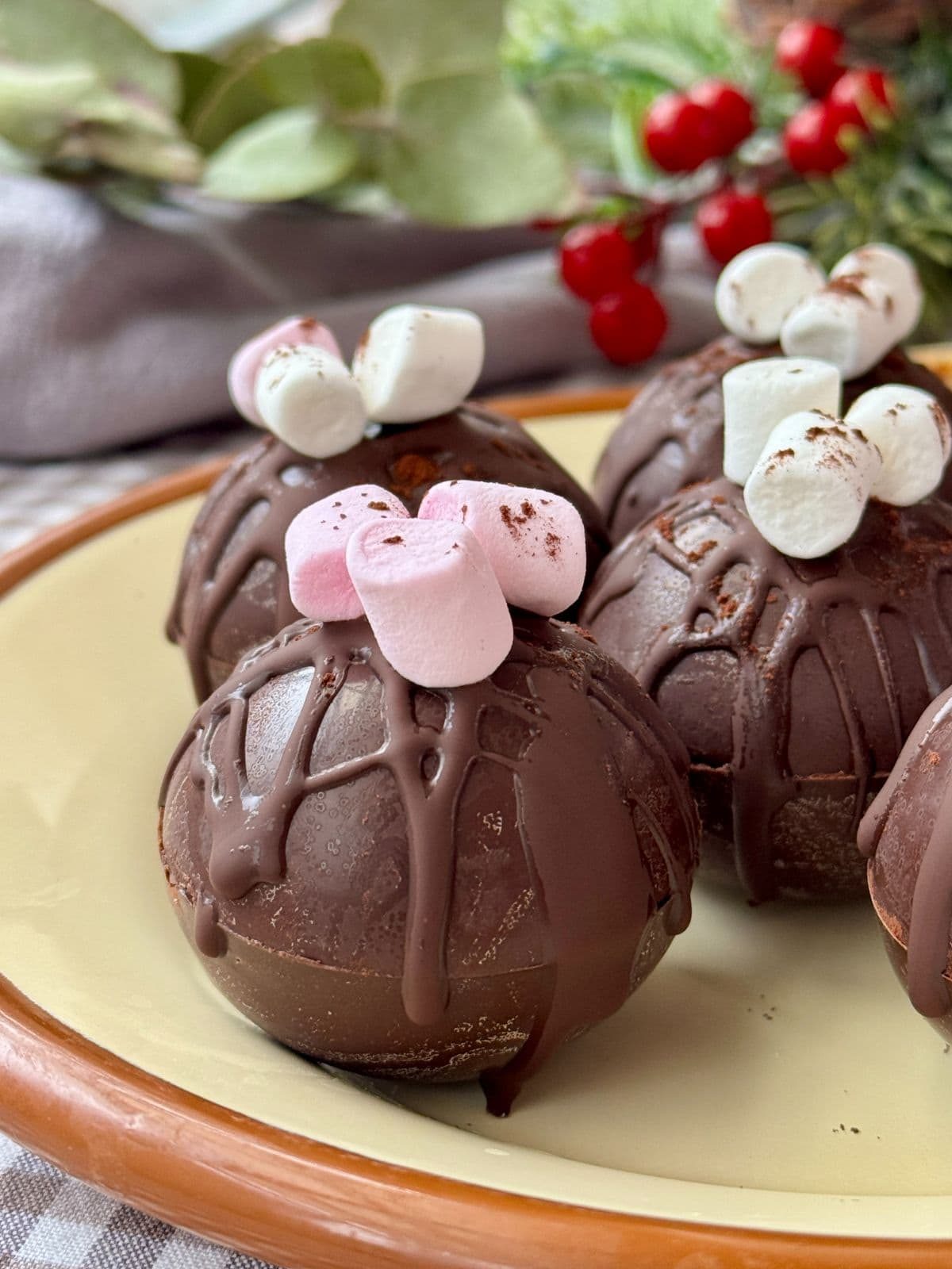 Hot chocolate bomb on a festive plate with marshmallows on top.