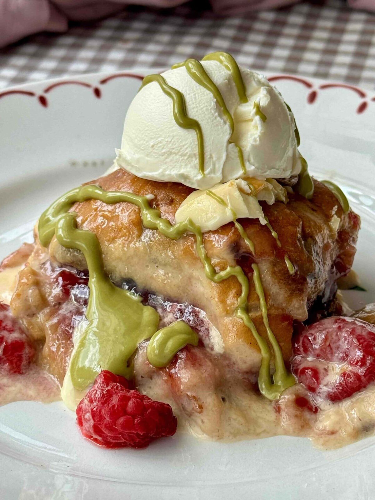 hot cross bun bread and butter pudding baked with white chocolate and raspberries drizzled with pistachio cream.