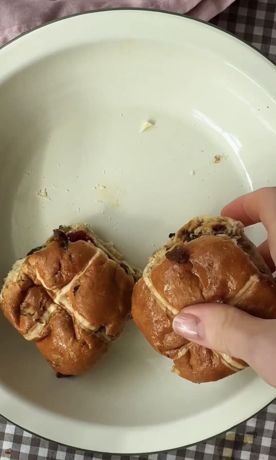 laying hot cross buns in a dish.