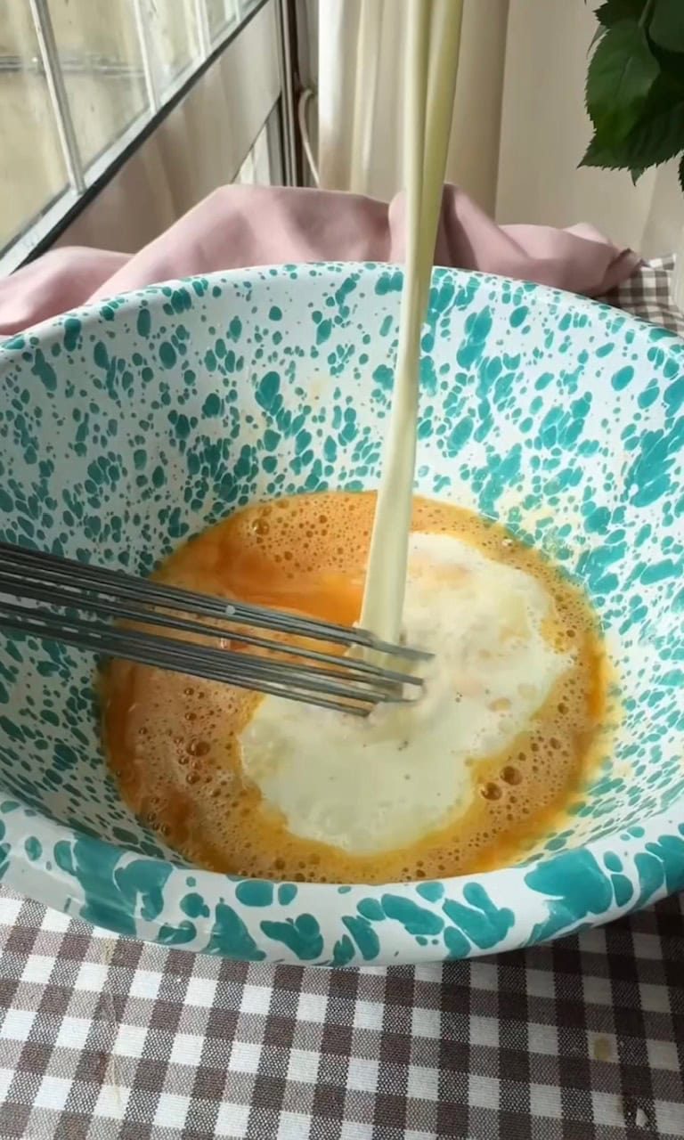 adding hot milk to eggs to make custard.