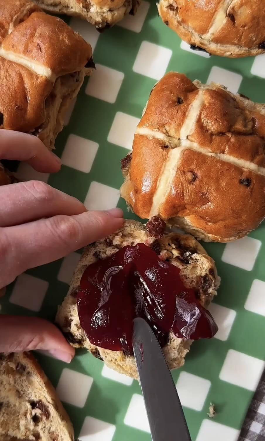 spreading jam on hot cross bun.