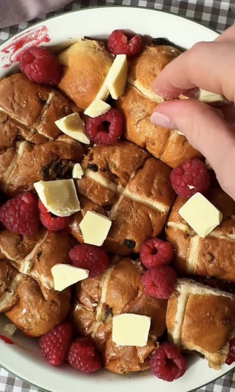 adding white chocolate and raspberries to hot cross bun bread and butter pudding.