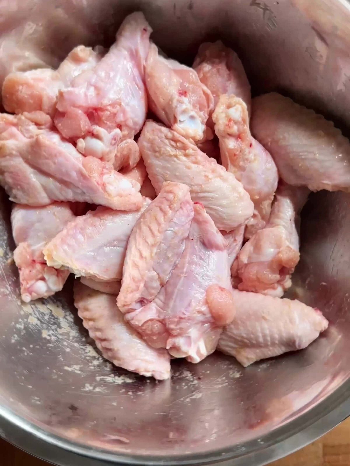 Fresh chicken wings in large bowl.