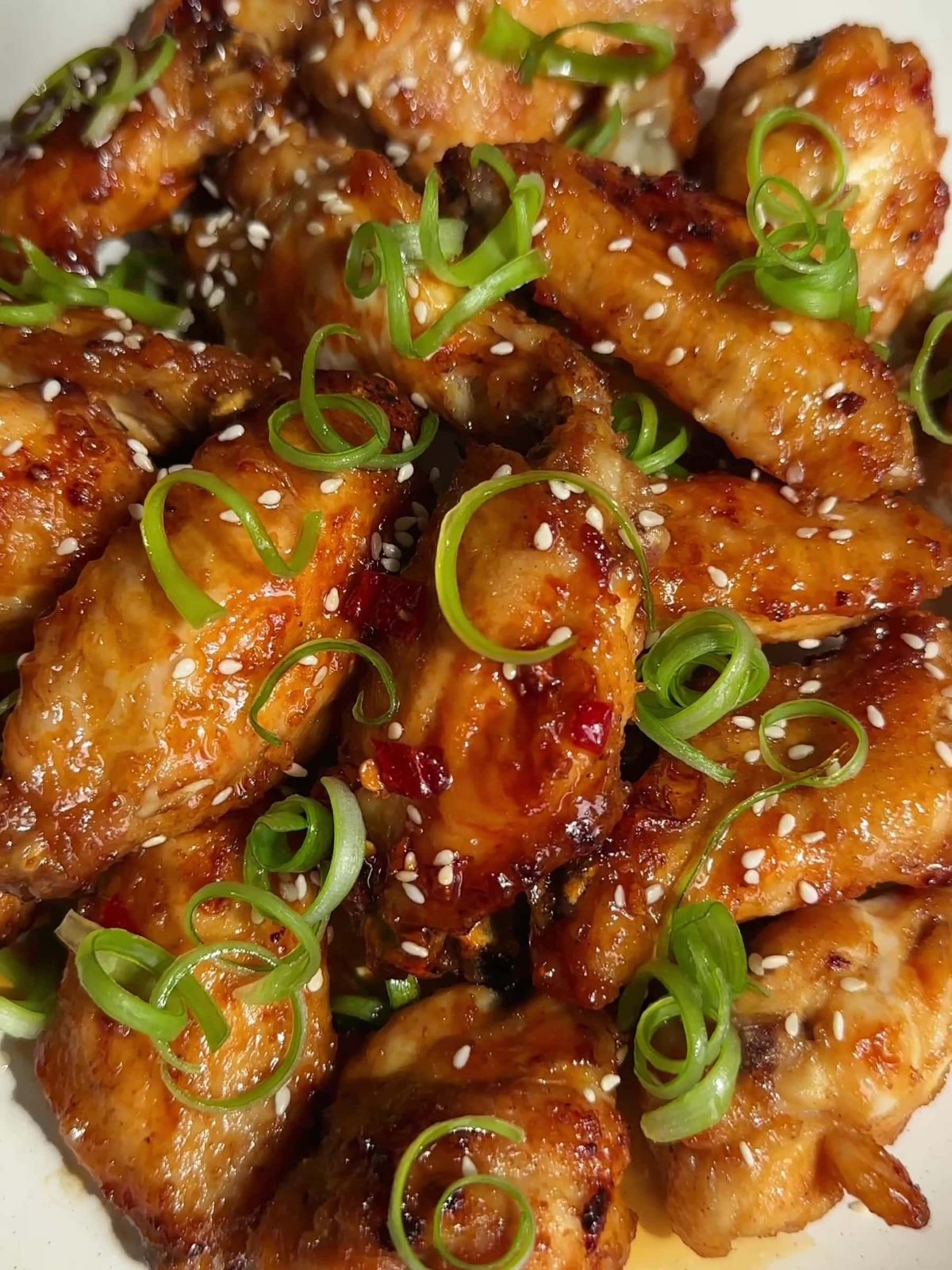 Hot honey chicken wings with chopped scallions and sesame seeds.