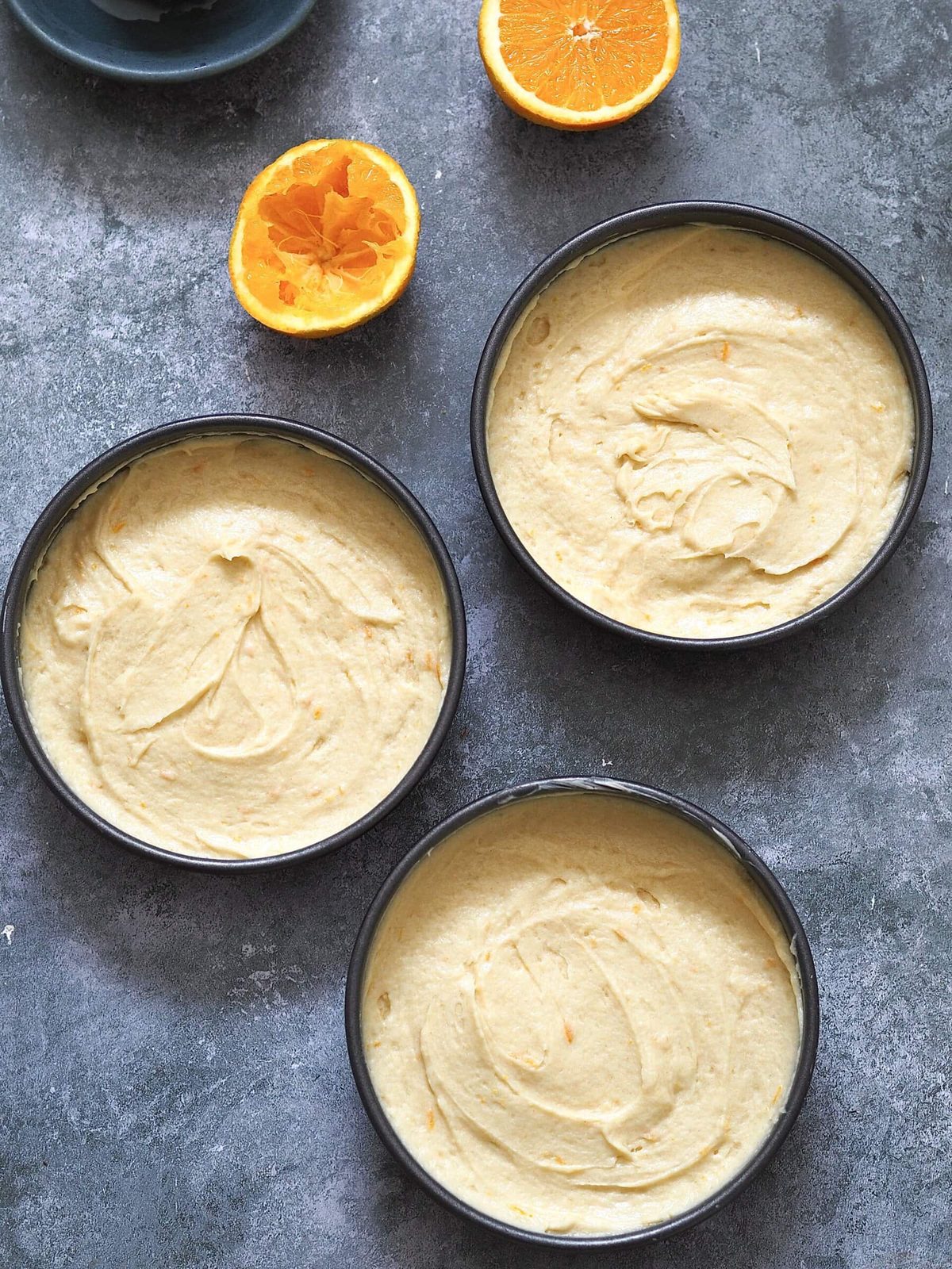 Three round cake pans filled with batter.