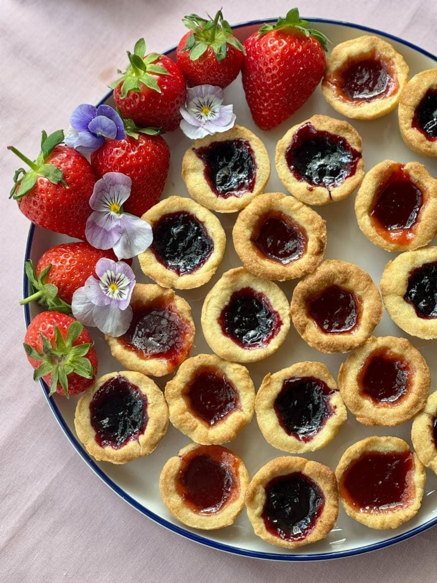 jam tartlets on a plate with edible flowers.
