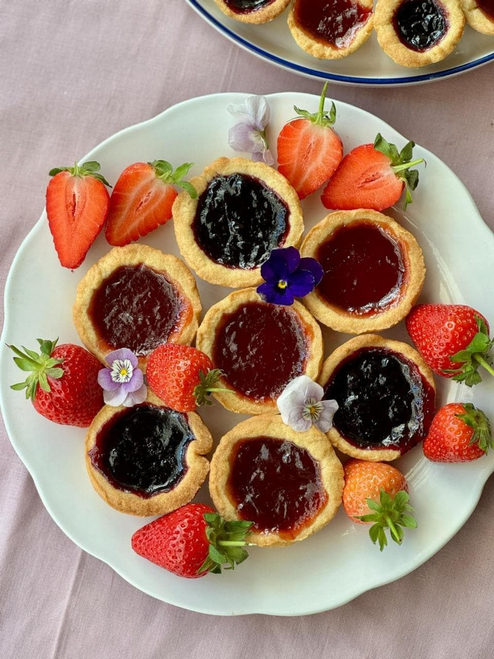 jam tartlets on a plate with edible flowers.