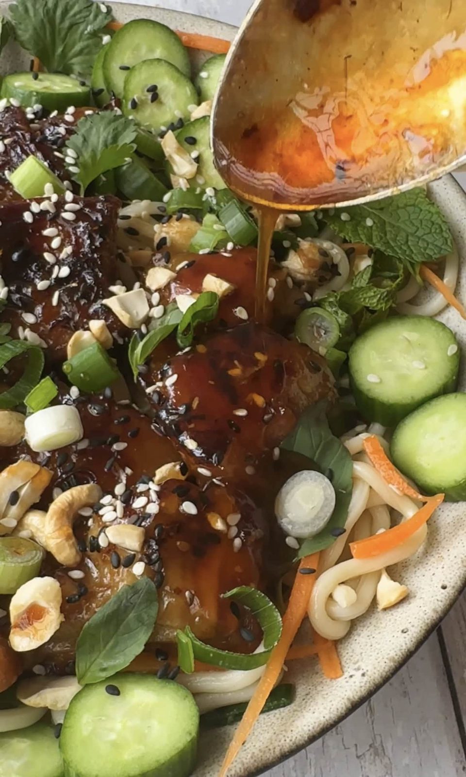 Drizzling sauce over the pork belly noodles.