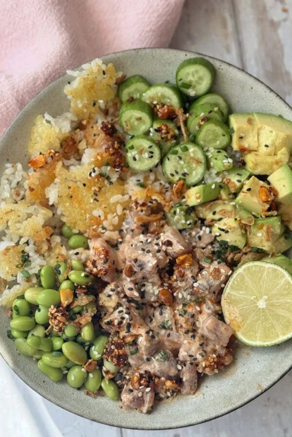 Spicy tuna in a bowl with crispy rice and cucumber and avocado.