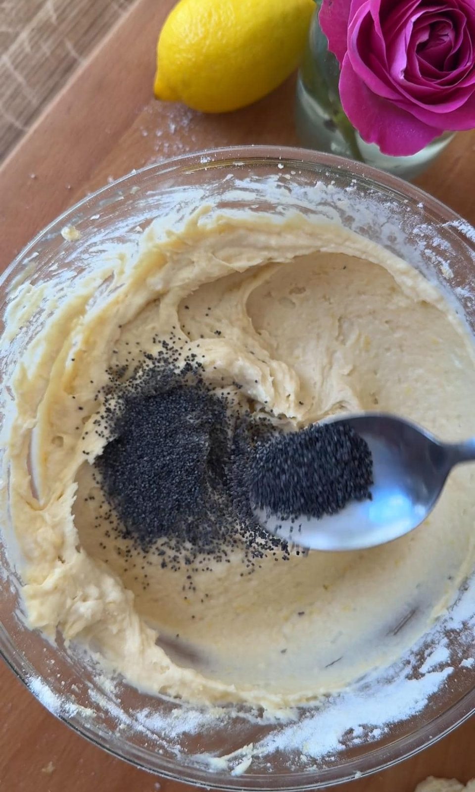 Adding poppy seeds to muffin batter in bowl.