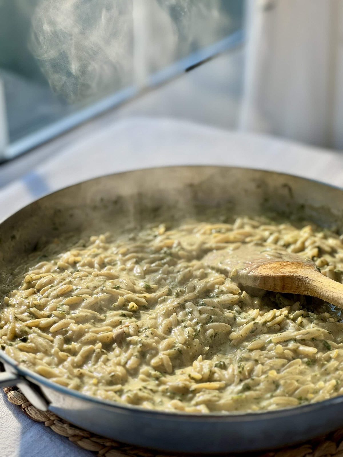 Steaming pan of lemon orzo with wood spoon.