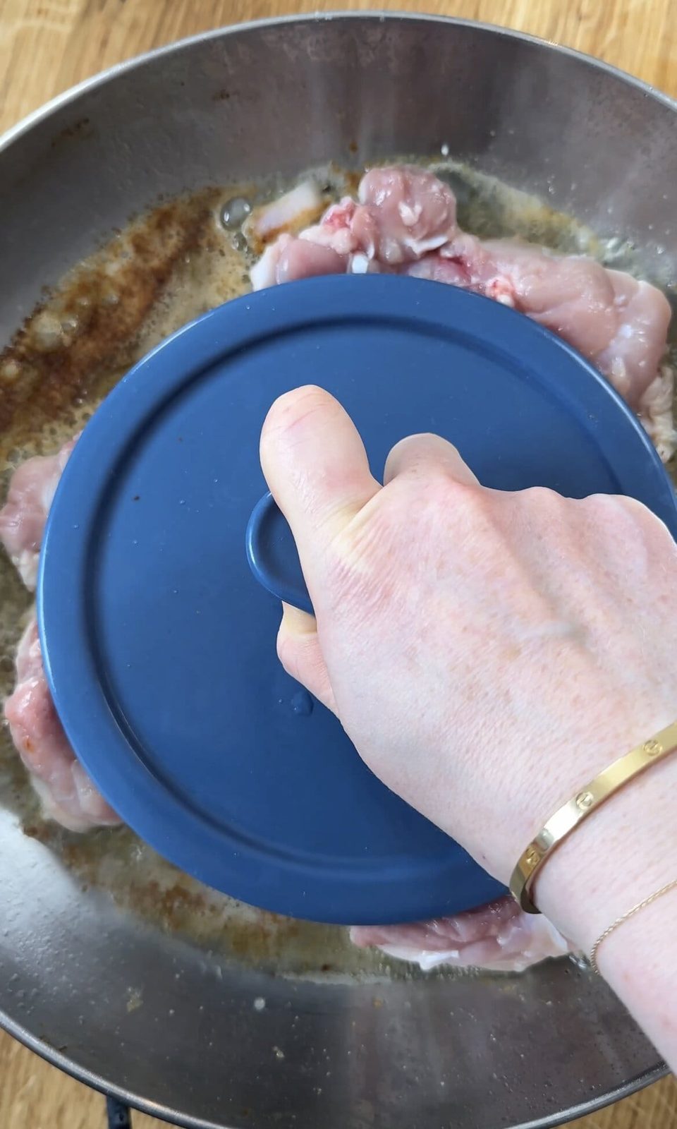 Weighted chicken thighs being pressed for crispy skin.
