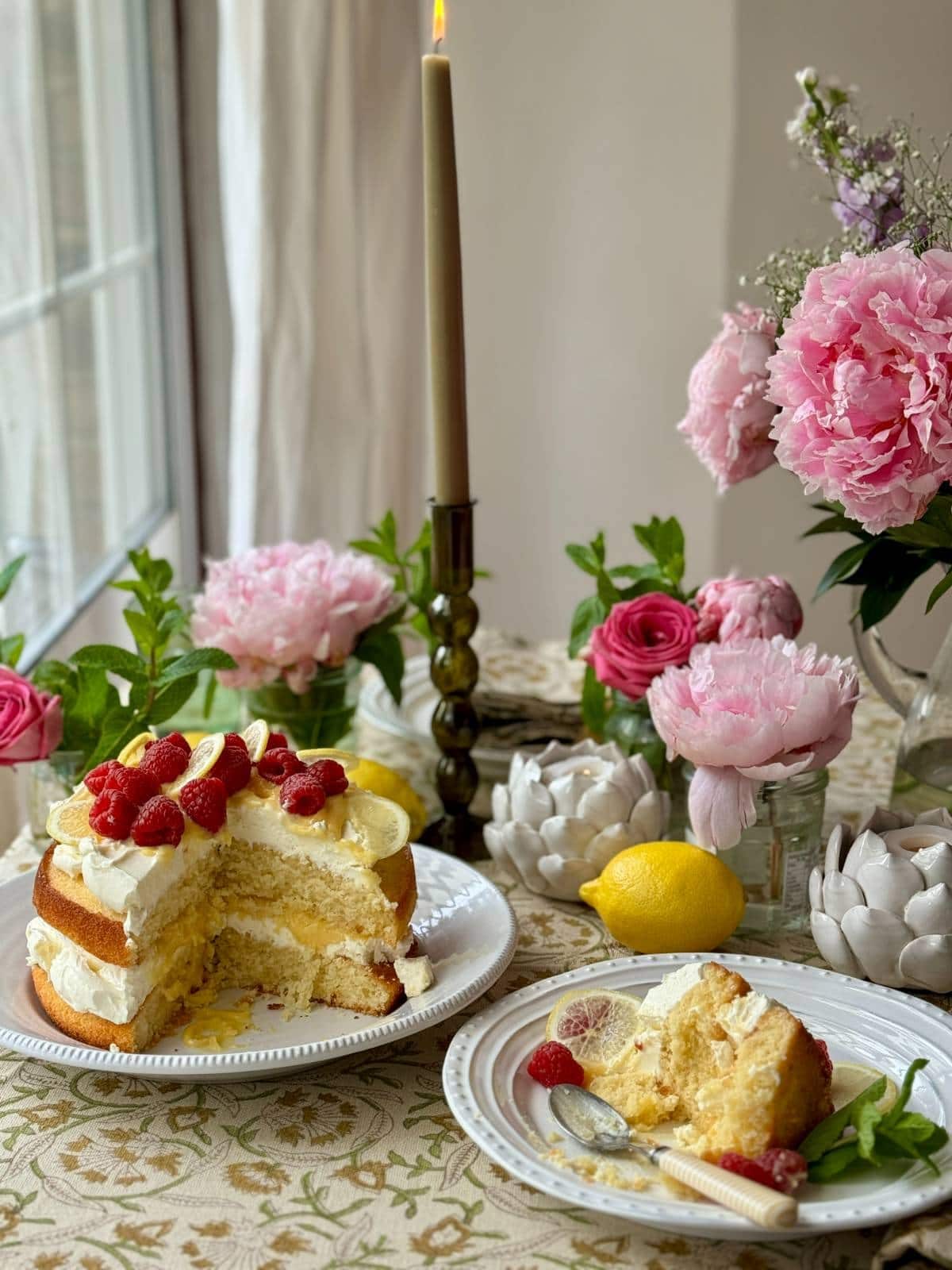 slice of lemon curd cake on a small plate with whole lemon curd cake behind it.