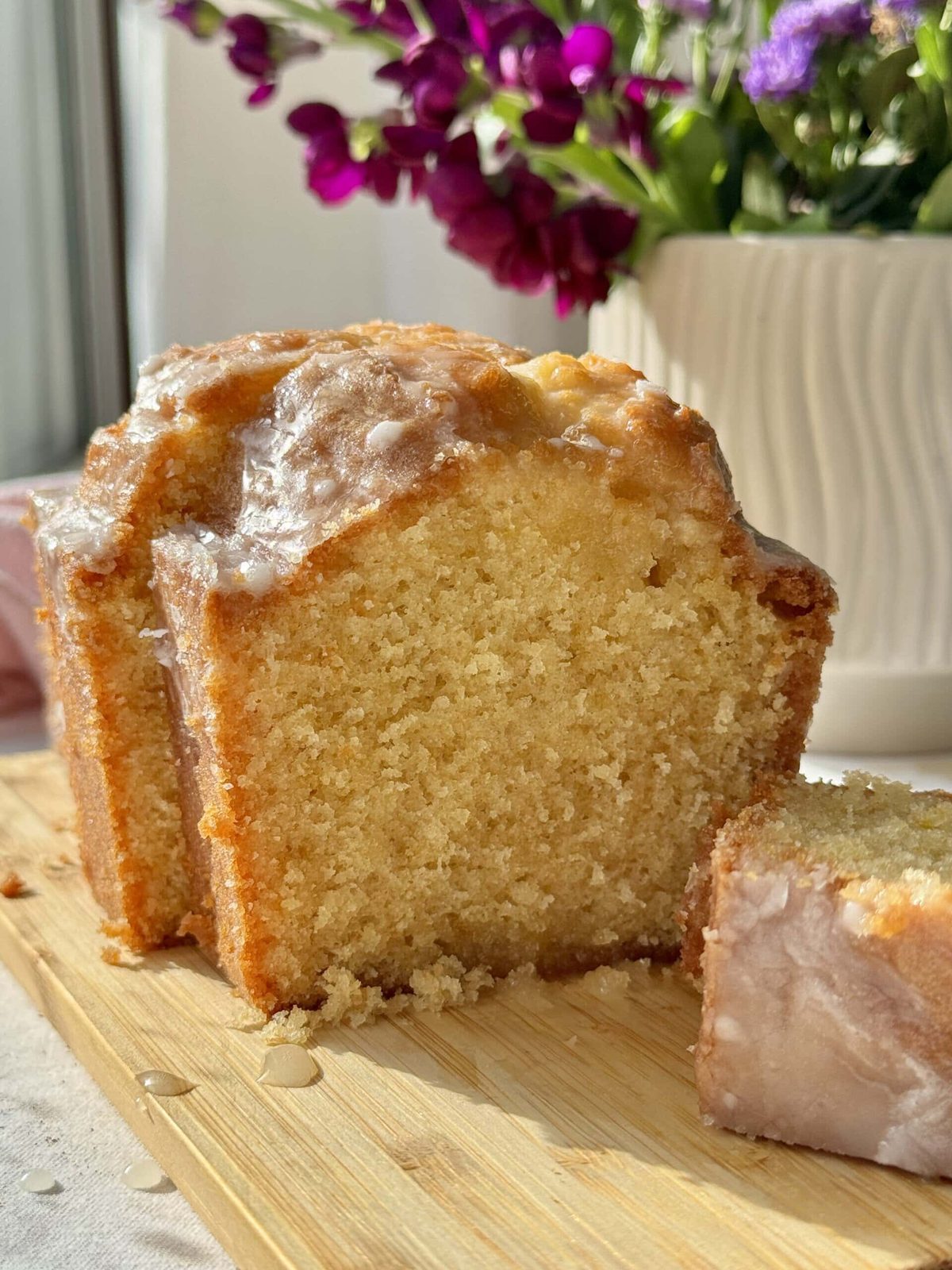 Slices of lemon loaf cake on wooden board.