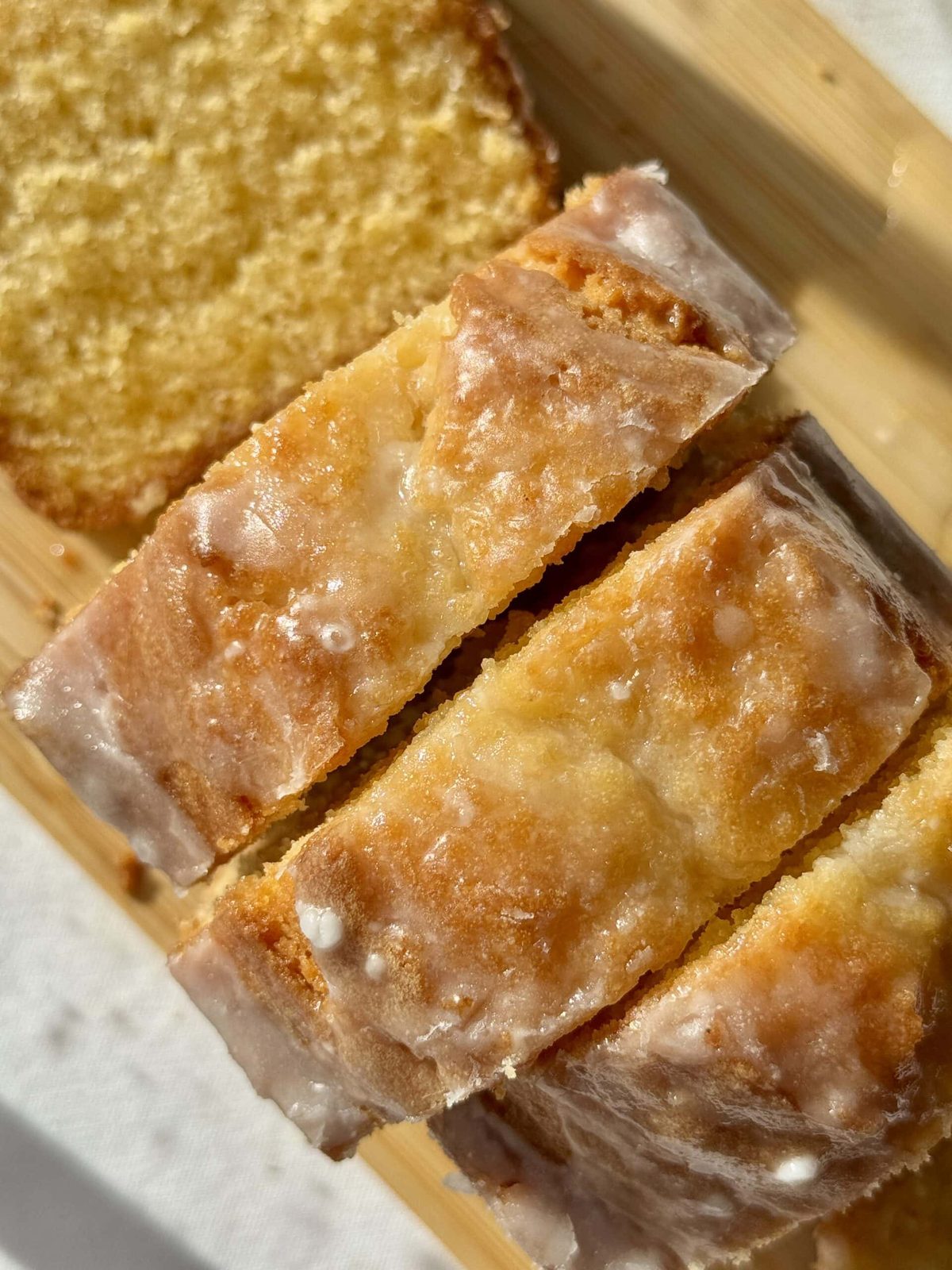 Sliced lemon cake with glaze on serving platter.