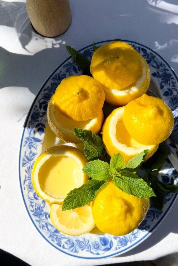 lemon possets in scooped out lemon halves on a blue plate.