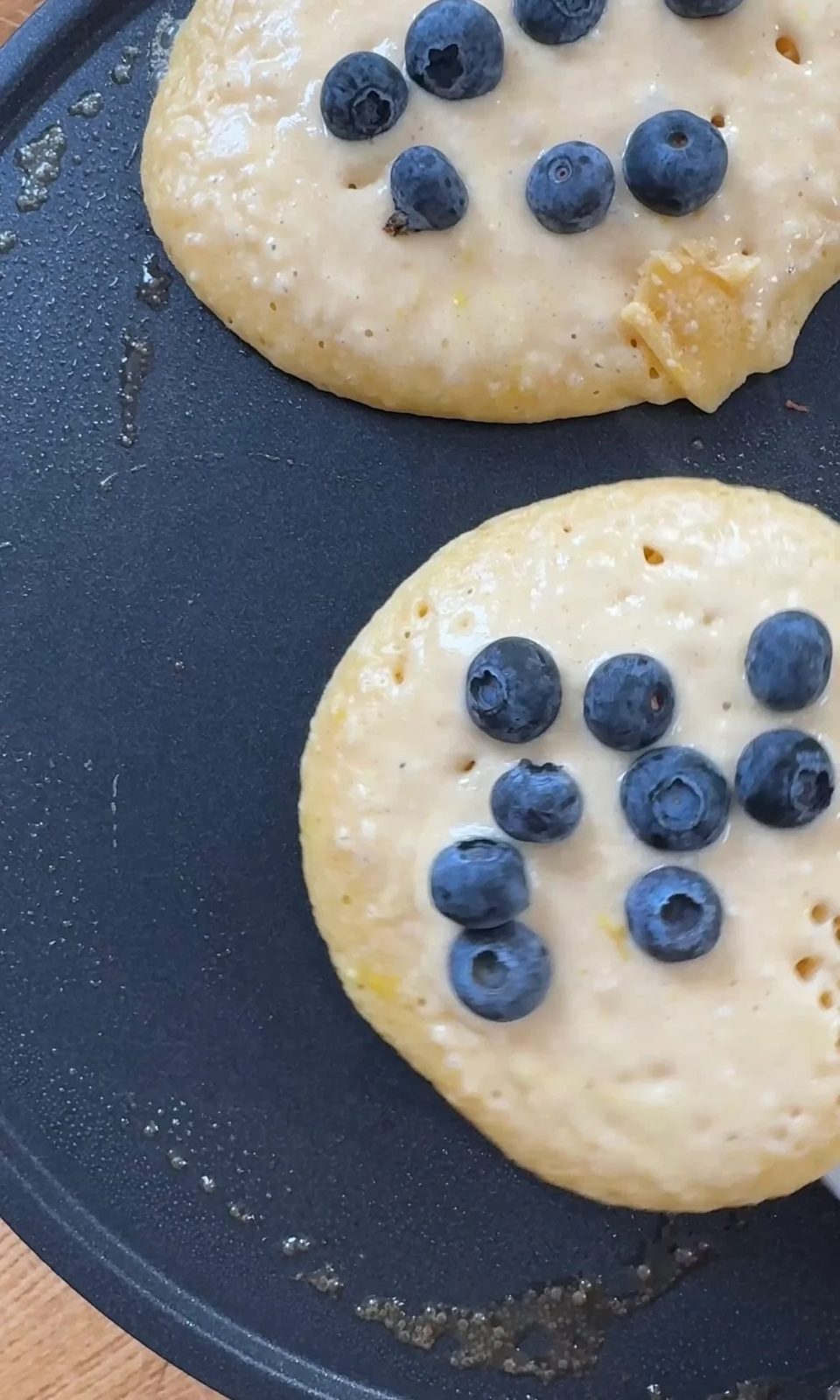 topping with blueberries when frying lemon ricotta blueberry pancakes.
