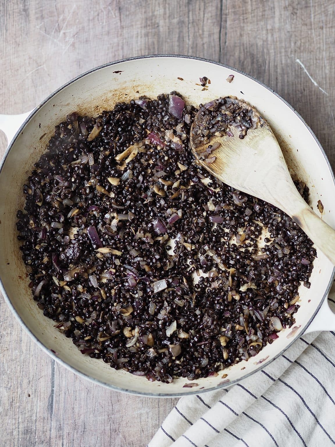 Lentils being stirred into a shallow casserole dish.