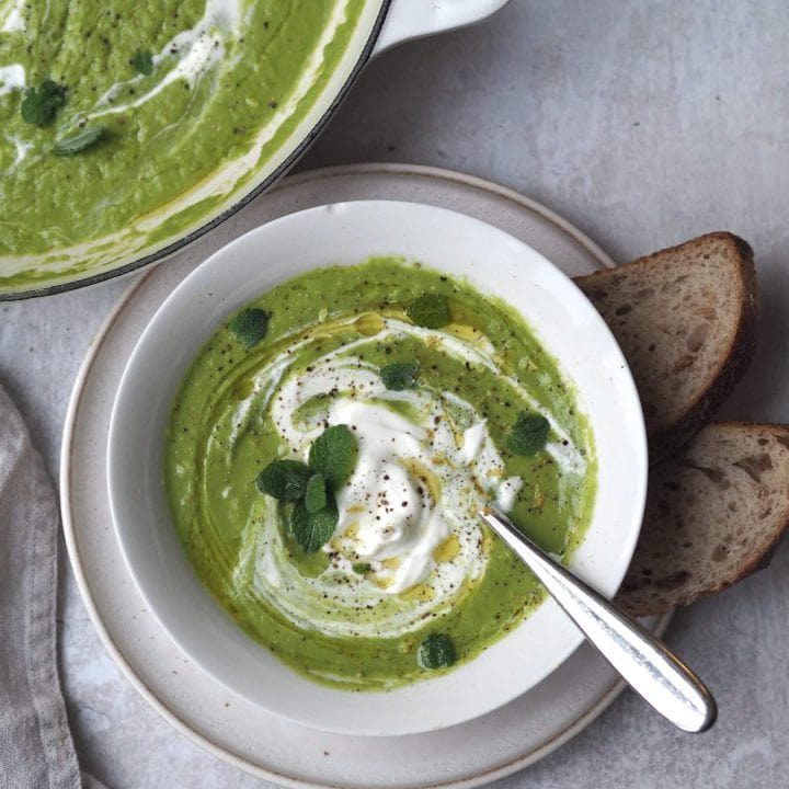 little gem, pea, mint soup in a white bowl with a pan of soup next to it