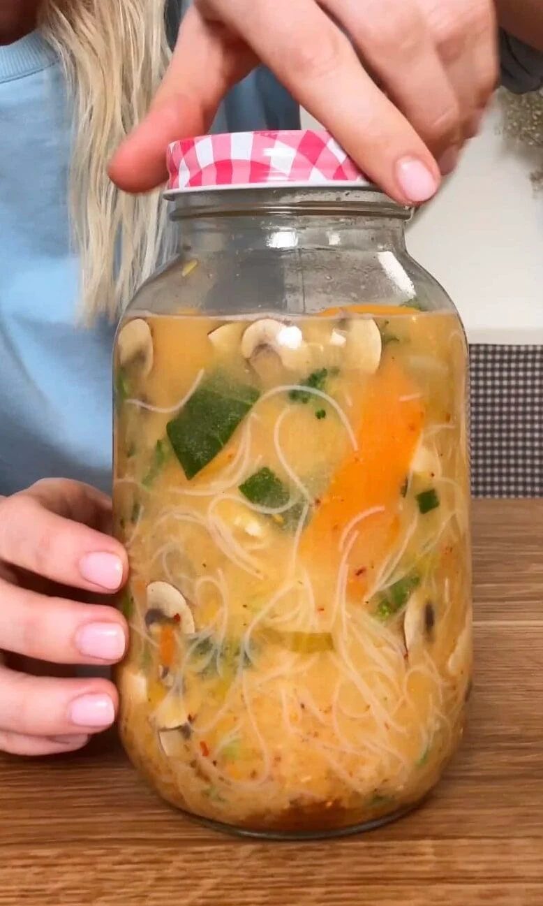 adding the lid to the mason jar noodles.