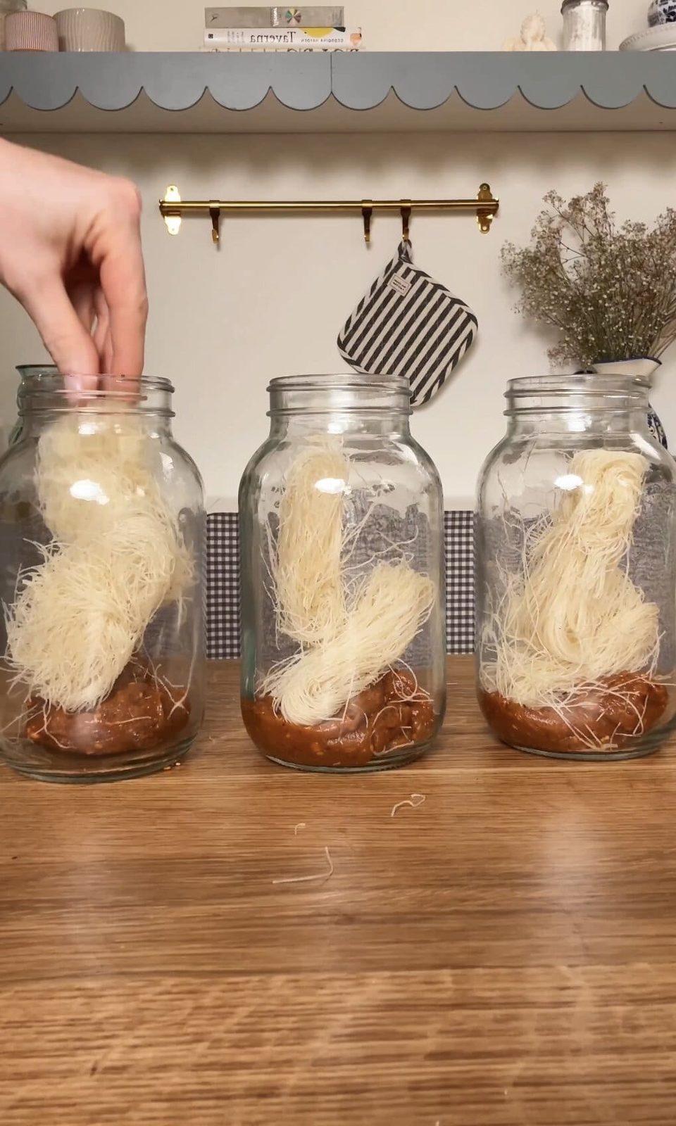 mason jar noodles lined up adding noodles.