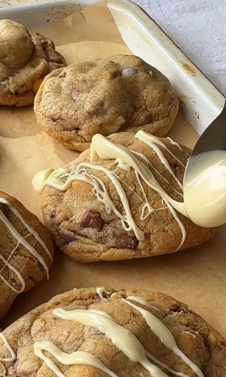 drizzling white chocolate on mini egg cookies.